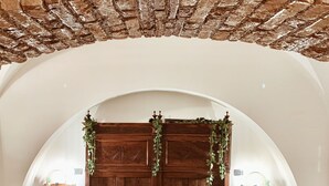 A bedroom with a wooden bed, arched ceiling, and a brick wall.