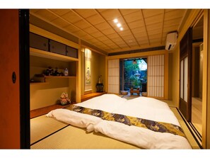 Experience serene tranquility in this traditional Japanese-style bedroom with a large bed and sliding shoji screen door leading to a garden.