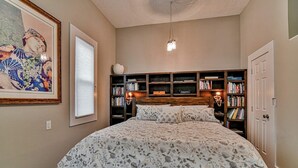 Une chambre à coucher avec un grand lit, une bibliothèque et un ventilateur de plafond.