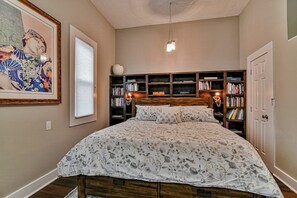 Een slaapkamer met een groot bed, een boekenkast en een plafondventilator.