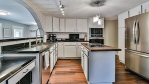 Une cuisine moderne avec des meubles blancs, des appareils en acier inoxydable et un îlot central.