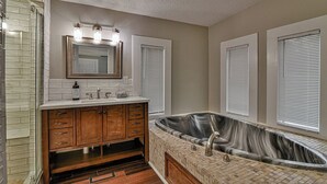 A bathroom with a large bathtub, wooden vanity, and a mirror with lights. - Asheville Rustic Cabin: Hot Tub, Pets ok, Fire Pit (Asheville)