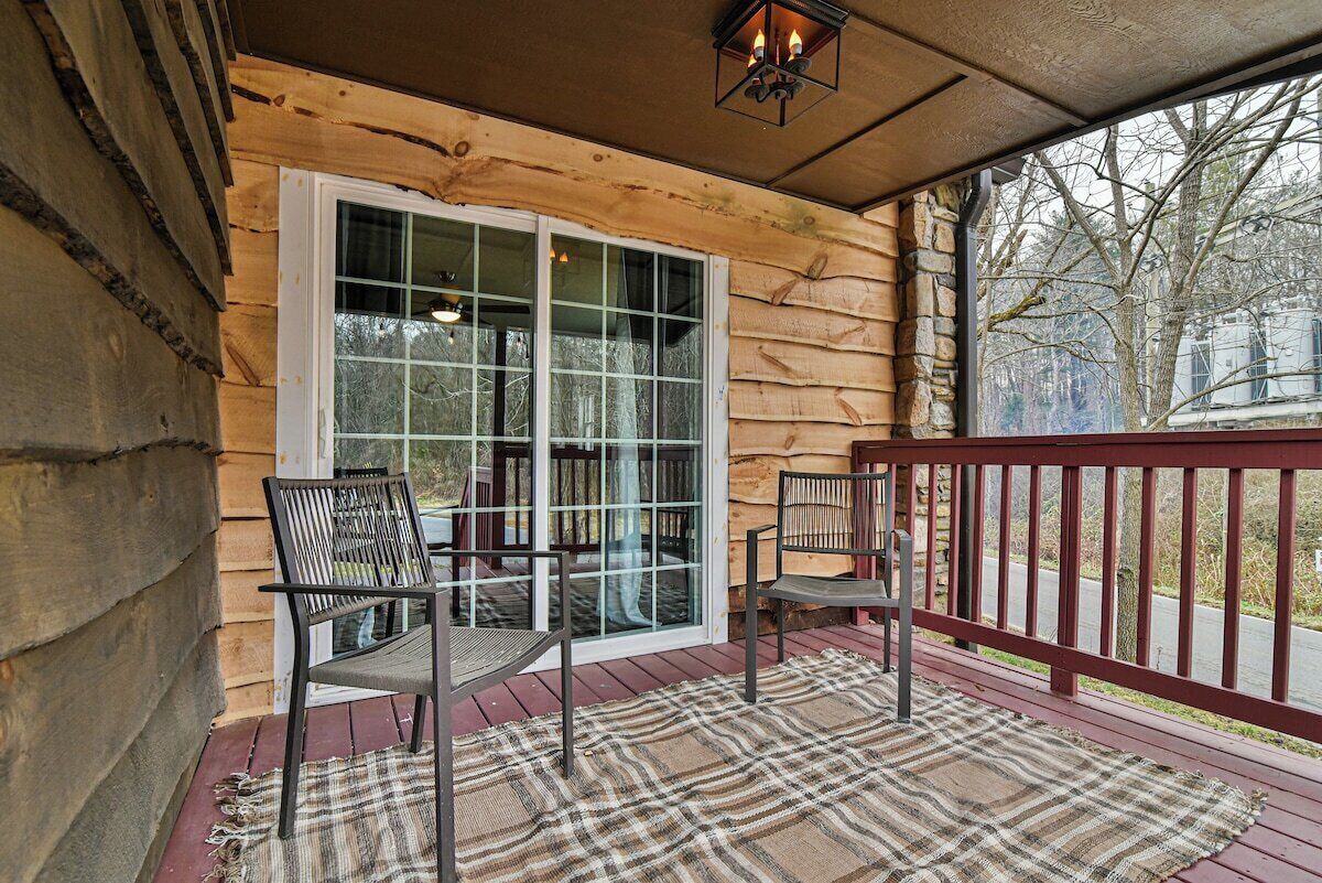 A wooden cabin with a porch, two chairs, and a large window.