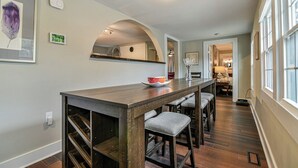 A dining area with a long wooden table, cushioned bar stools, and a mirror above. - Asheville Rustic Cabin: Hot Tub, Pets ok, Fire Pit (Asheville)