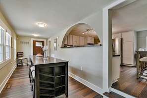 A modern kitchen with an archway, wooden flooring, and built-in cabinets.
