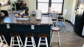 A kitchen with a central island, bar stools, a dining table, and chairs. - Lily’s Pad 5 minute drive from the Interlochen Arts accademy (Interlochen)