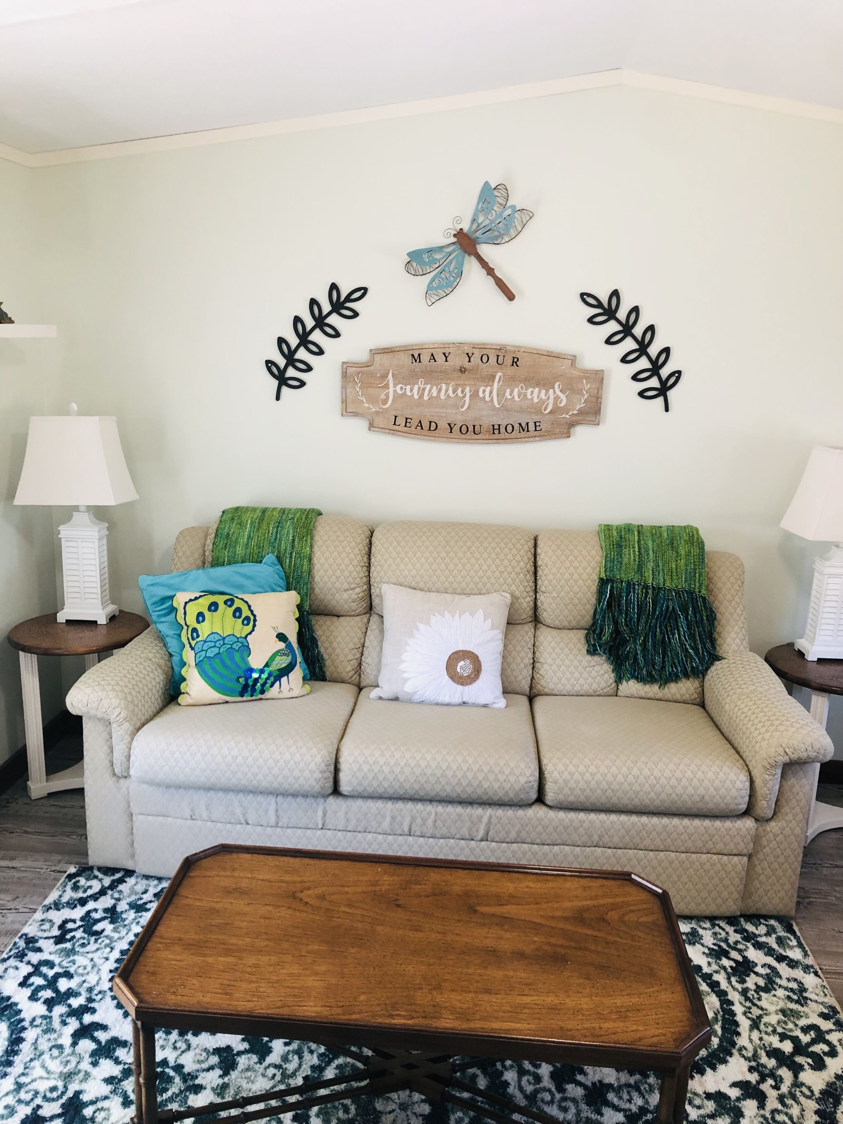 A living room with a beige sofa, decorative pillows, a wooden coffee table, and wall art.