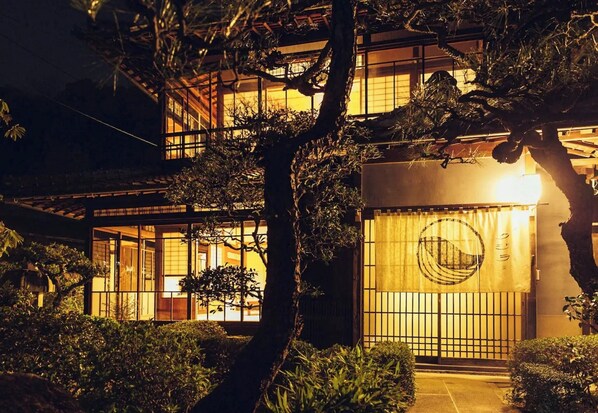 A traditional Japanese building with a wooden exterior, large windows, and a well-lit entrance.