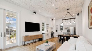 Ein modernes Wohnzimmer mit einem weißen Sofa, einem Couchtisch und einem an der Wand befestigten Fernseher.