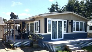 Una casa móvil de un piso con porche cubierto, un patio y un pequeño jardín.