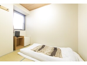 Simple, functional room with a single bed, desk, and tatami mat flooring.