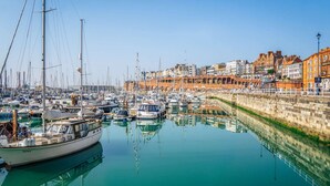 A marina with boats docked, a stone wall, and buildings with arches in the background. - Beautiful Apartment on Ramsgate Sea-front (Ramsgate)