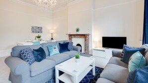 Ein modernes Wohnzimmer mit grauem Sofa, einem weißen Couchtisch, einem Kamin und einer Deckenleuchte.