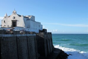 Une église située sur la côte, dotée d’un mur en briques et offrant une vue sur l’océan.