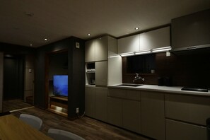 Una cocina moderna con electrodomésticos integrados, un comedor con mesa de madera e iluminación empotrada.