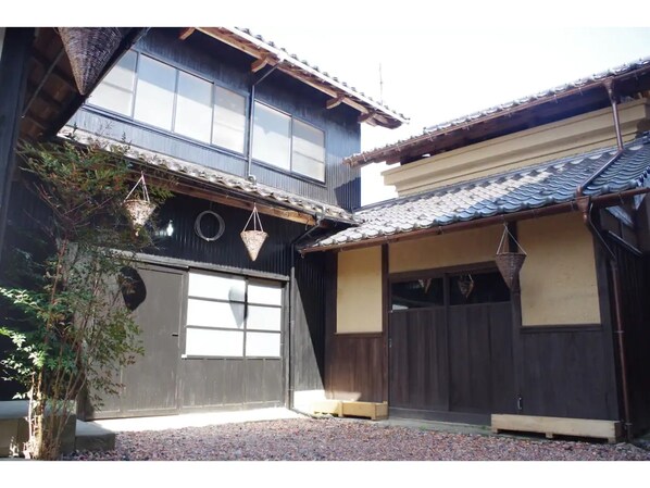 Traditional Japanese-style building with a two-story structure, featuring a large entrance door, windows, and a tiled roof.