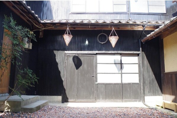 Traditional Japanese-style building with a large wooden door and a serene garden.