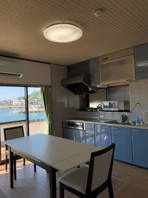 Una cocina moderna con vistas a un cuerpo de agua, un comedor con mesa y sillas, y un ventanal grande.