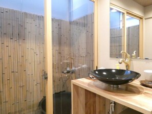 Bathroom features a glass door, vessel sink, and gold faucet.