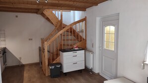A room with a wooden staircase, a white door with a frosted glass window, and a white dresser with drawers. - Kleines Ferienhaus im Zentrum von Bad Schandau (Bad Schandau)