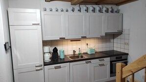 A kitchen with white cabinets, a black countertop, and various appliances including a coffee maker, toaster, and sink. - Kleines Ferienhaus im Zentrum von Bad Schandau (Bad Schandau)