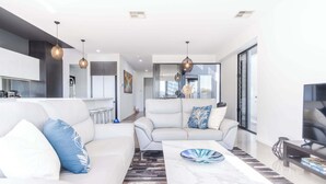 A modern living room with a sofa, coffee table, and pendant lights. - Luxury Lakeside Living at Birtinya (Birtinya)