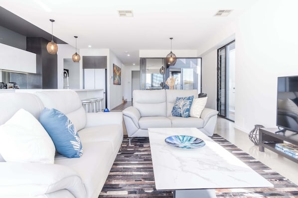 A modern living room with a sofa, coffee table, and pendant lights.