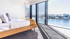 A bedroom with a large window, a bed, and a view of a body of water. - Luxury Lakeside Living at Birtinya (Birtinya)