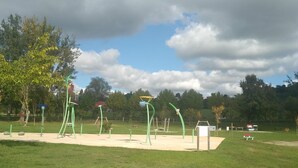 Un parque al aire libre con equipamiento verde para hacer ejercicio y un arenero.