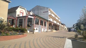 Un hotel con fachada moderna, un cartel que indica hotel y restaurante, y un camino pavimentado al frente.