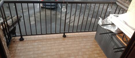 Een balkon met uitzicht op een parkeerplaats.