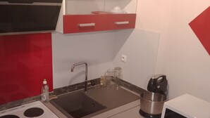 Una cocina compacta con estufa, pileta y microondas.