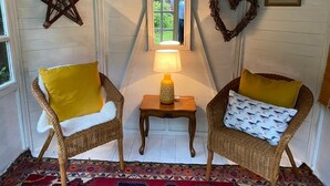 Una habitación acogedora con dos sillones de mimbre, una mesita con una lámpara, una estrella decorativa, un adorno en forma de corazón y un cuadro en la pared.