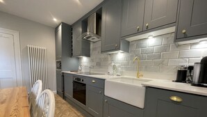 Una cocina moderna con armarios grises, encimera blanca y suelo con estampado de espiga.