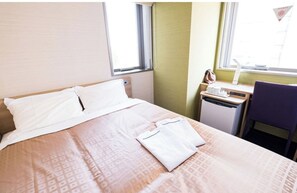 Relax in a cozy space with a neatly made bed and a desk area near a window offering a view.