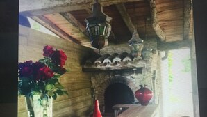 Ein rustikales Interieur mit einer Holztresen, einer Vase mit roten Blumen, einer roten Flasche und einem gefliesten Boden.
