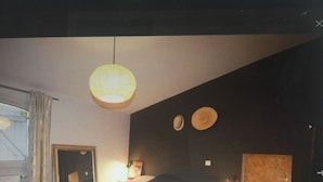 A bedroom with a bed, bedside table, lamp, and a mirror on the wall. - Belle Demeure en Pierre (Bon-Encontre)