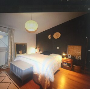 Un dormitorio con cama, mesita de noche, lámpara y un espejo en la pared.
