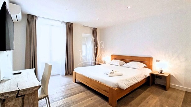 A hotel room with a wooden bed, a desk, a chair, and a TV. - Viva Riviera 3 bedrooms Natural Loft Luxury Collection (Cannes)