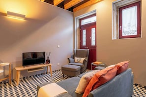 A modern living room with a TV, sofa, armchair, and ottoman.