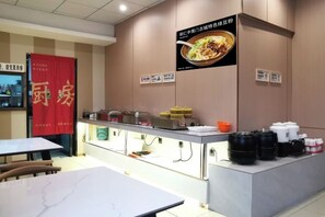 A restaurant with a counter, tables, and a red banner.
