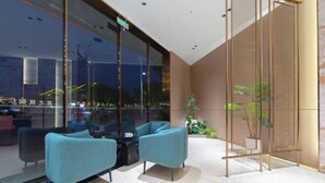 A modern indoor seating area with two sofas and a small table, a glass partition, and a wooden panel wall. - Tongren Grand Hotel (Tongren High-speed Railway Station Ancient City Pedestrian Street Branch) (Tongren)