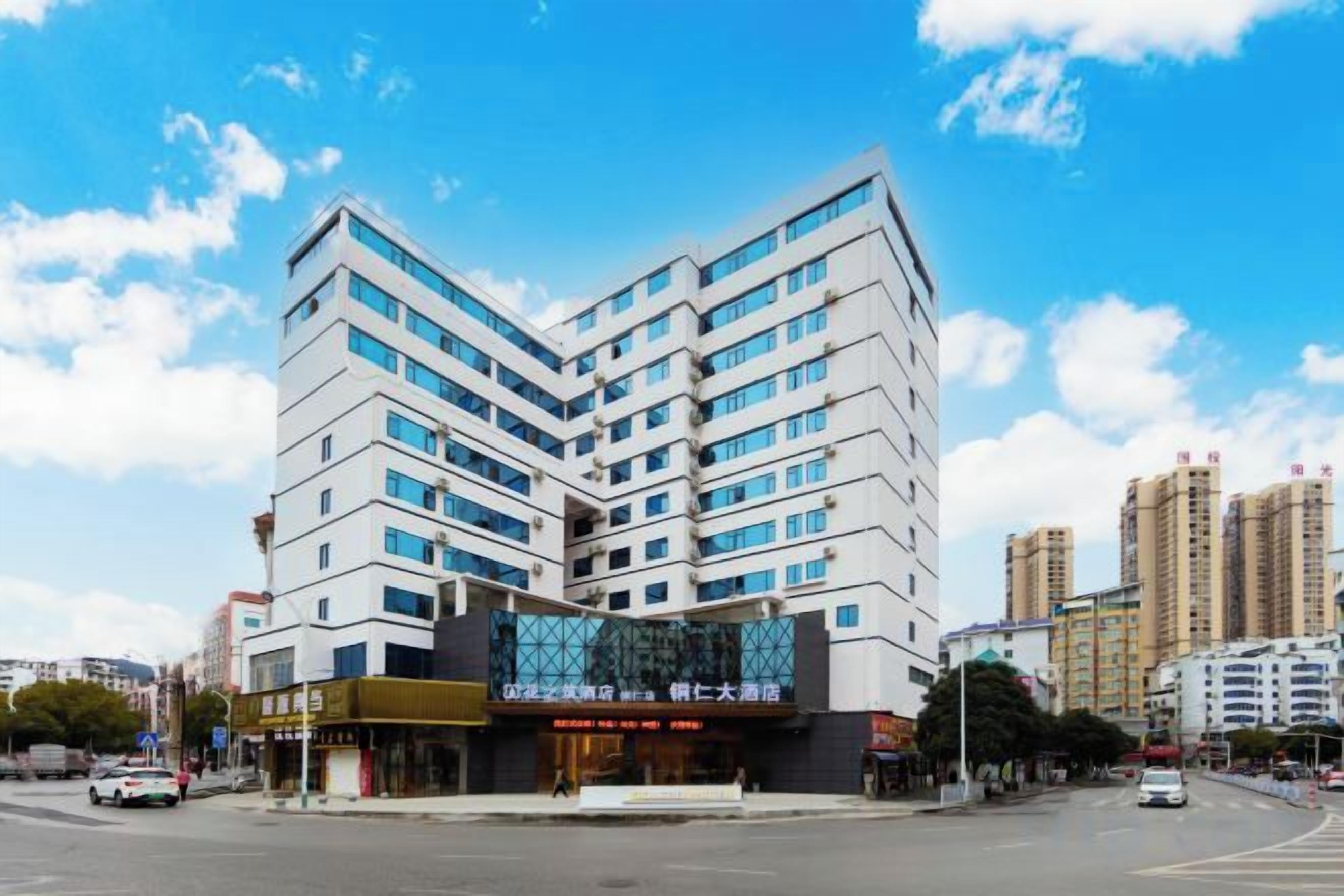 A multi-story hotel with a modern design, featuring a prominent glass facade and a corner location at an intersection.