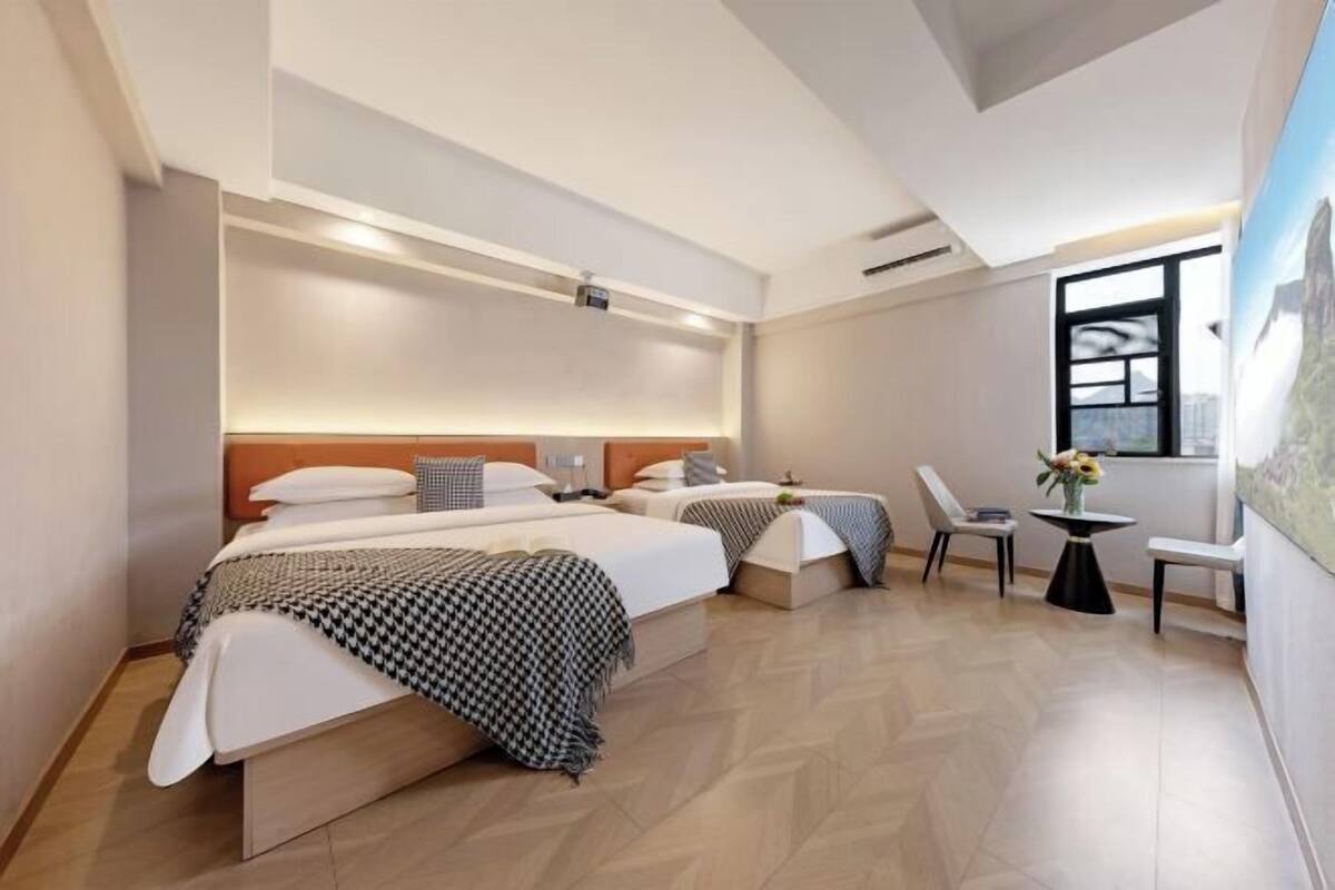 Moderni hotellihuone, jossa on kaksi sänkyä, pieni pöytä ja tuoli.