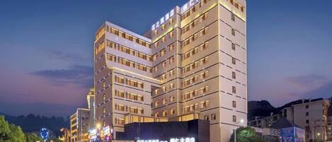A multi-story hotel with a modern design, featuring a prominent corner structure and illuminated signage.
