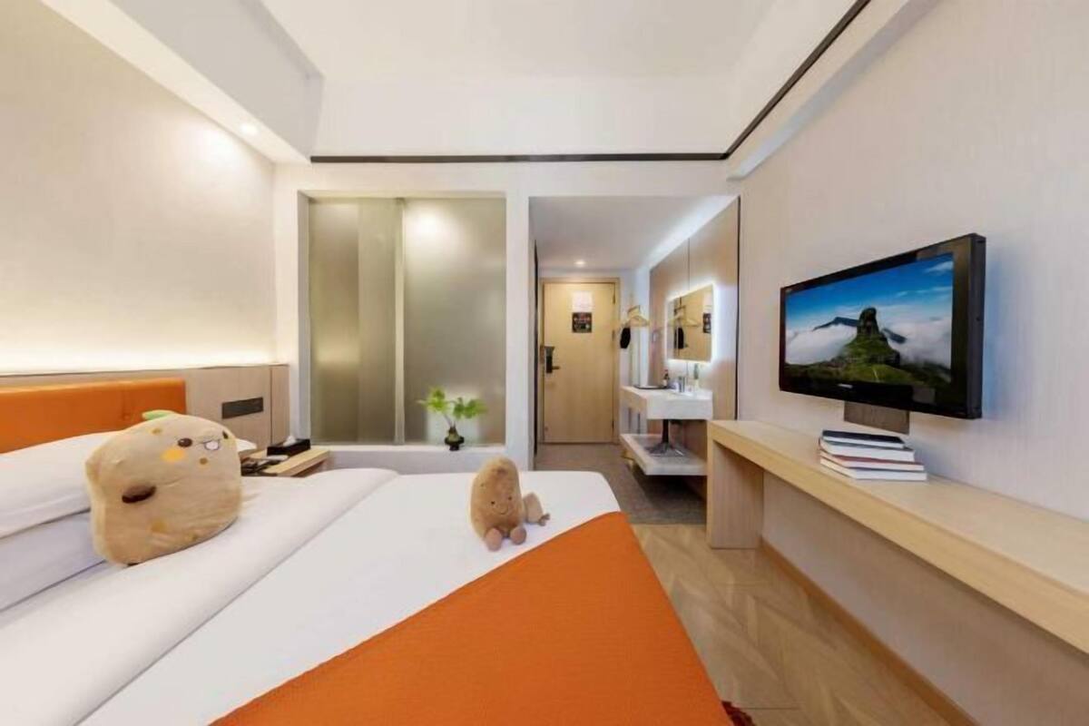 Hotellihuone, jossa on sänky, televisio, ikkuna ja taustalla näkyvä kylpyhuone.