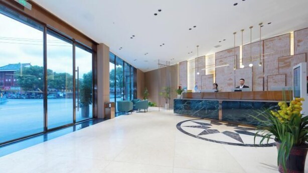 A modern hotel lobby with a reception desk, seating area, and large windows offering a view of the street. - Tongren Grand Hotel (Tongren High-speed Railway Station Ancient City Pedestrian Street Branch) (Tongren)