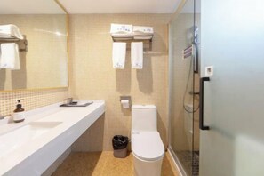 Un baño moderno con un lavabo blanco, un inodoro y una cabina de ducha con paredes de vidrio.