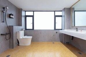 Un baño moderno con un ventanal grande, un lavamanos blanco y un inodoro.