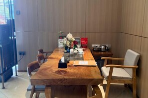 Una mesa de madera con sillas, un florero con flores, un bolso rojo y una tetera.
